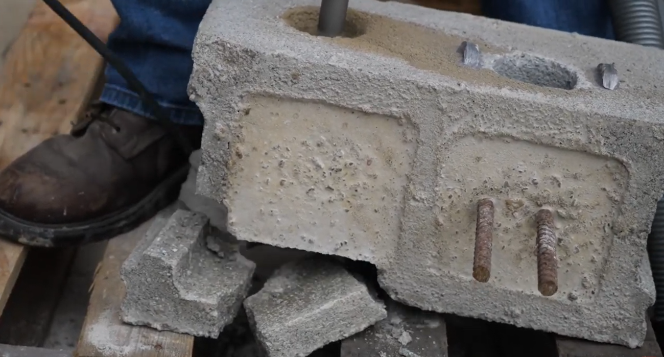 Drilling into concrete with a carbide core bit, resulting in busted concrete in the back from the impact of the carbide and rotary hammer.