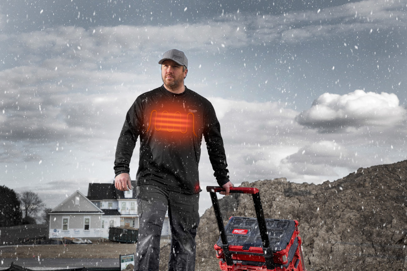 Worker pulling a packout wearing a Milwaukee heated workskin base layer in the rain