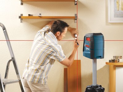 Worker using Bosch Red Cross-Point Laser Level to install shelving
