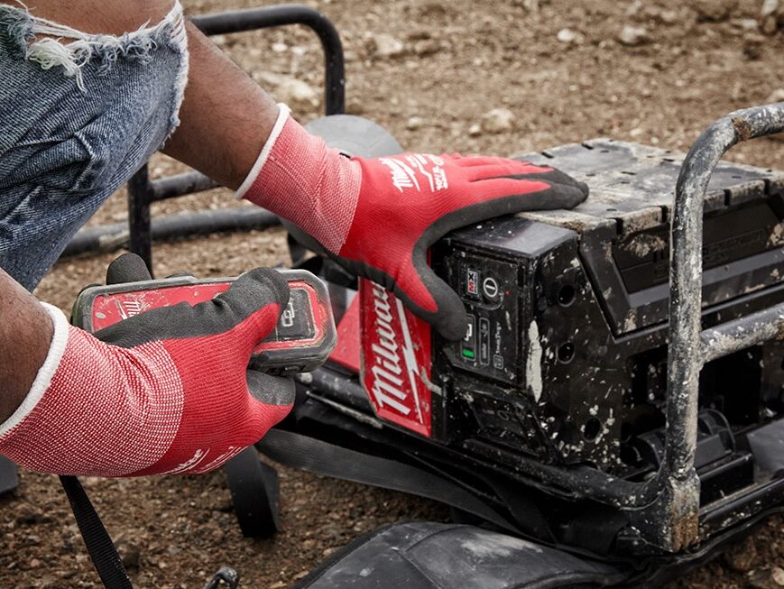Worker using remote to control the Milwaukee MX FUEL Backpack Concrete Vibrator Kit MXF371-2XC