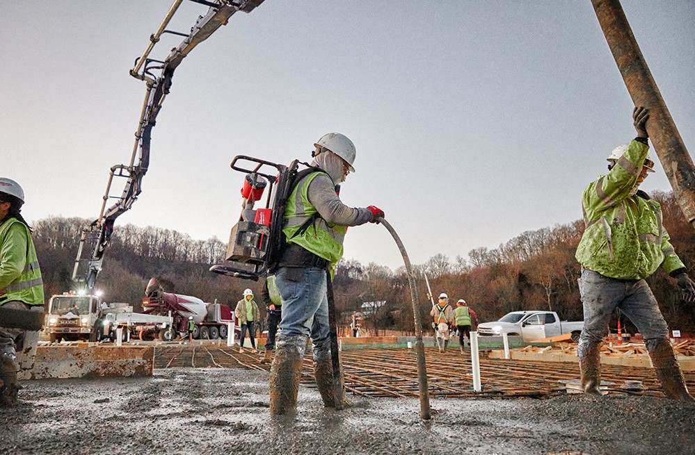 Construction worker consolidating concrete using the Milwaukee MX FUEL Backpack Concrete Vibrator Kit MXF371-2XC
