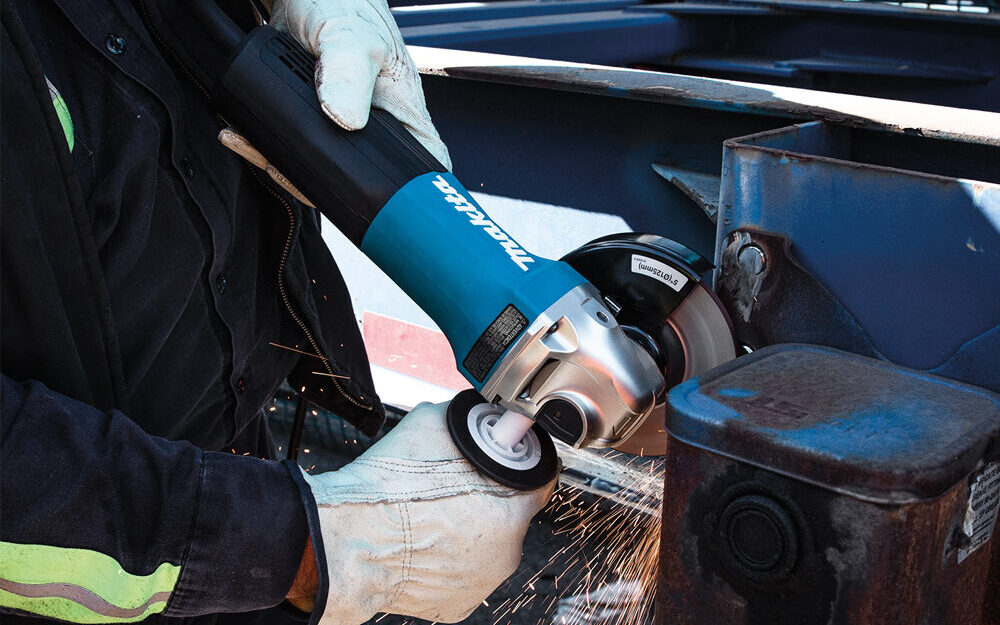 construction worker using a Makita angle grinder with a non-removable guard