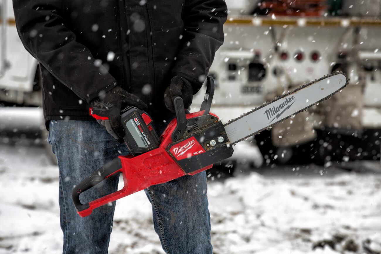 Man holding the new Milwaukee M18 14" Chainsaw. 